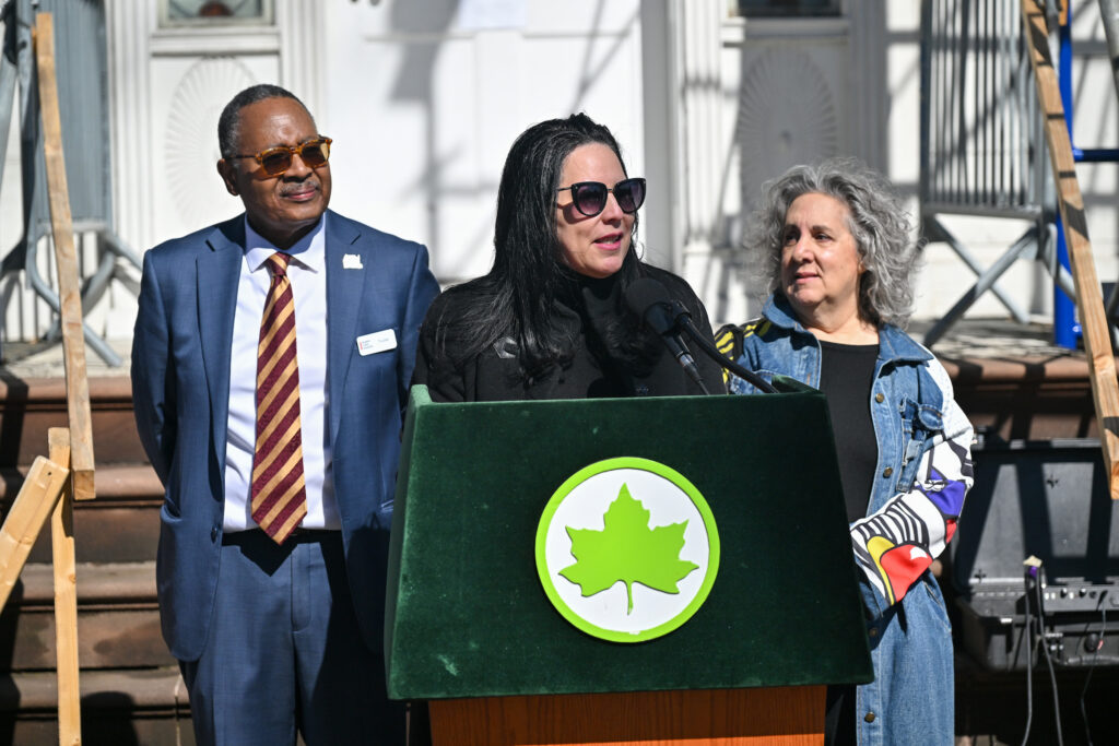 Photo of Wayne Benjamin, Luana Ferreira, and Alexis Marnel, who represented Community Board 12-Manhattan, behind a NYC Parks podium.