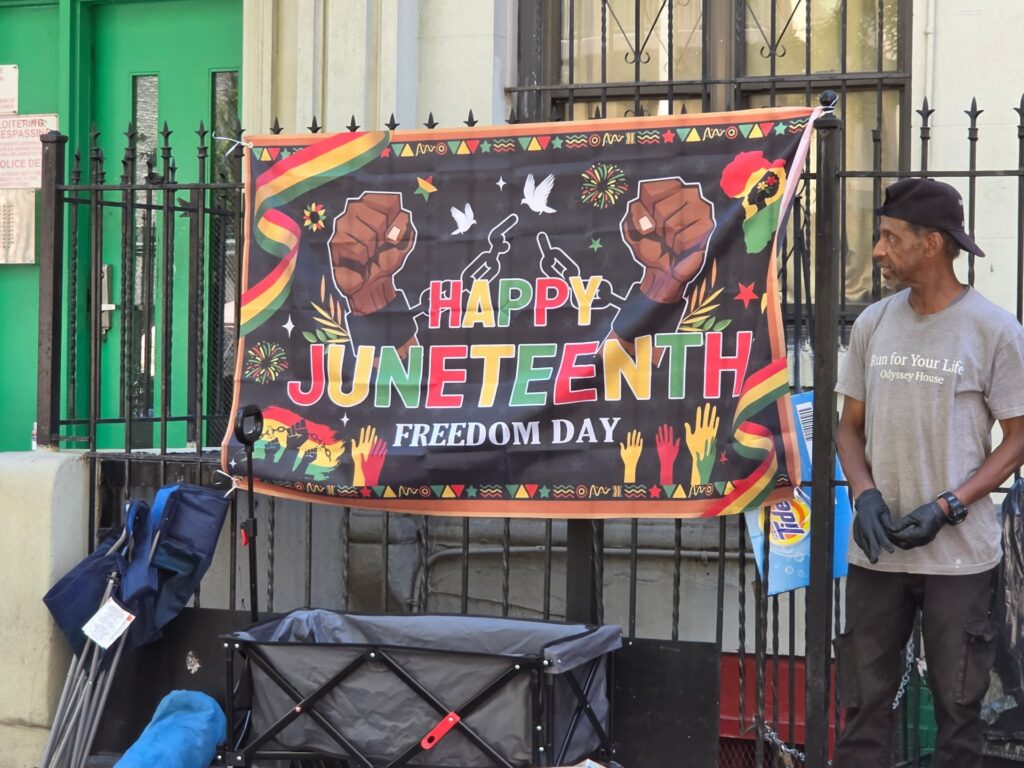An event volunteer is pictured with a "Happy Juneteenth" banner.